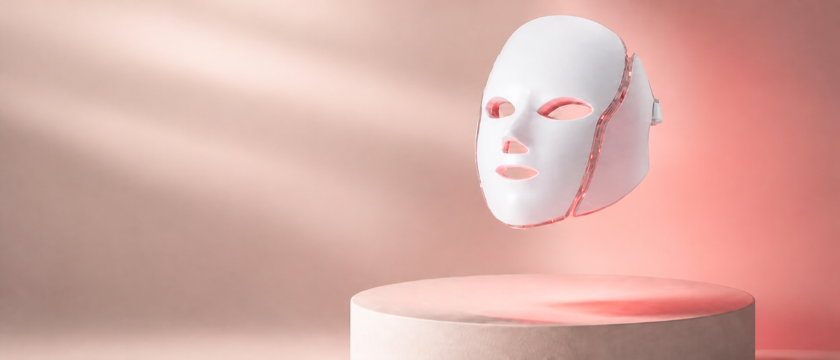 Wearable white LED face mask displayed on a premium blush pedestal